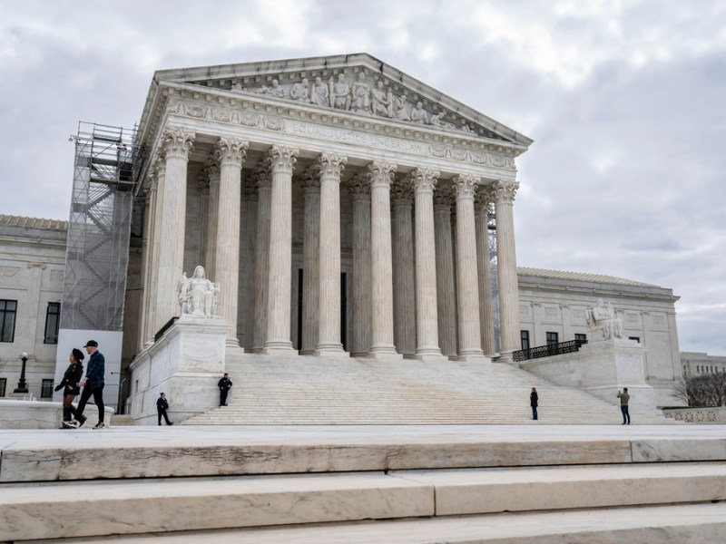 People walk by, some stopping to take photos, of the U.S. Supreme Court building