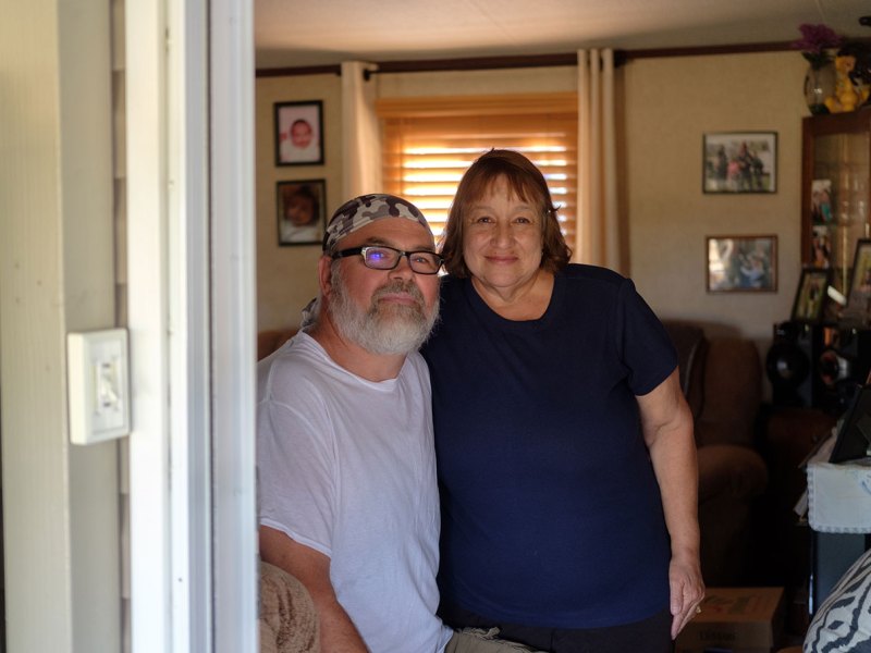 A man and a woman pose for a portrait in the door of their home in the La Luna Community Cooperative mobile home park