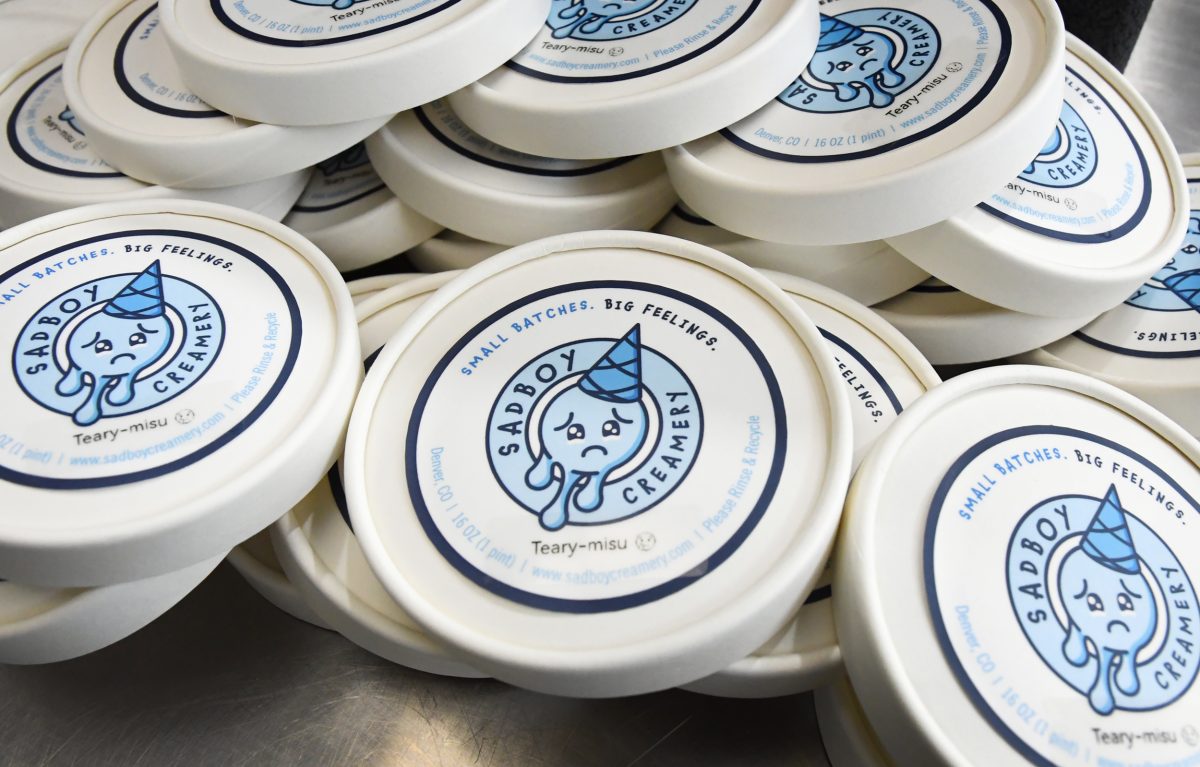 Stacks of round ice cream containers labeled "Sad Boy Creamery" with a cartoon crying face and the flavor "Teary-misu" on the lids.