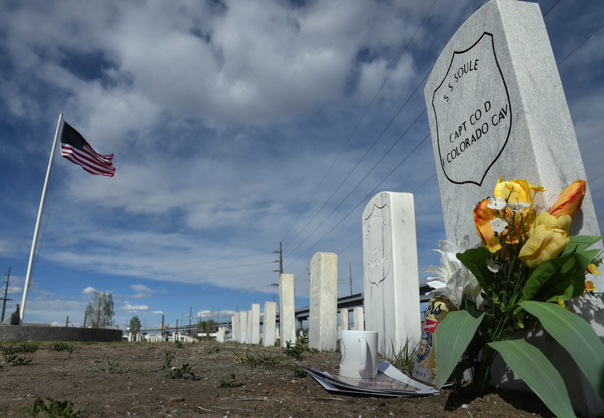 White marble headstones in straight lines at Riverside Cemetery in Denver. One is marked with flowers and other objects. It has the namee of Silas S. Soule inscribed above his rank, captain in the Colorado Cavalry.